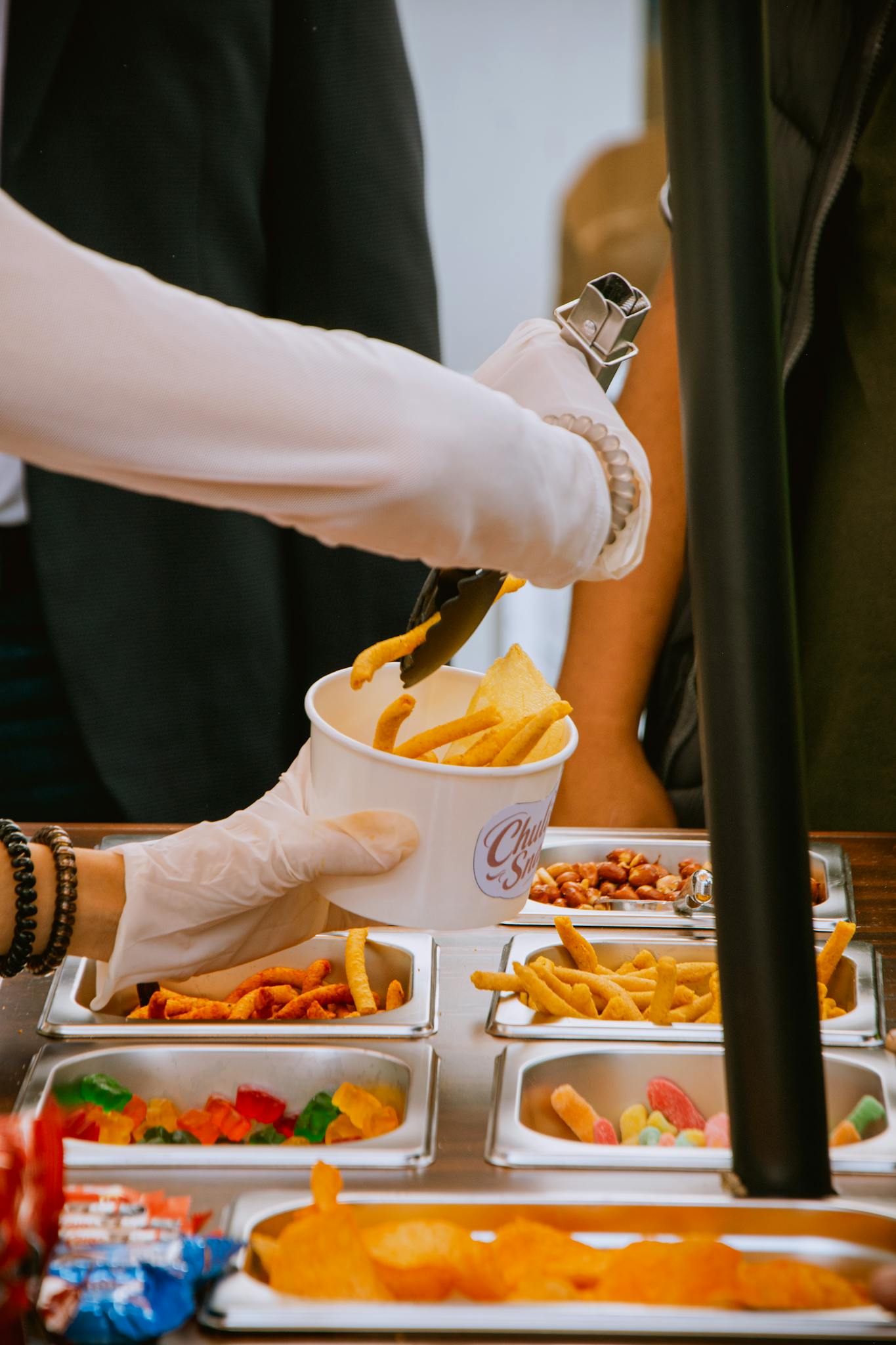 Image of a street food vendor serving fries from a variety of snacks outdoors.